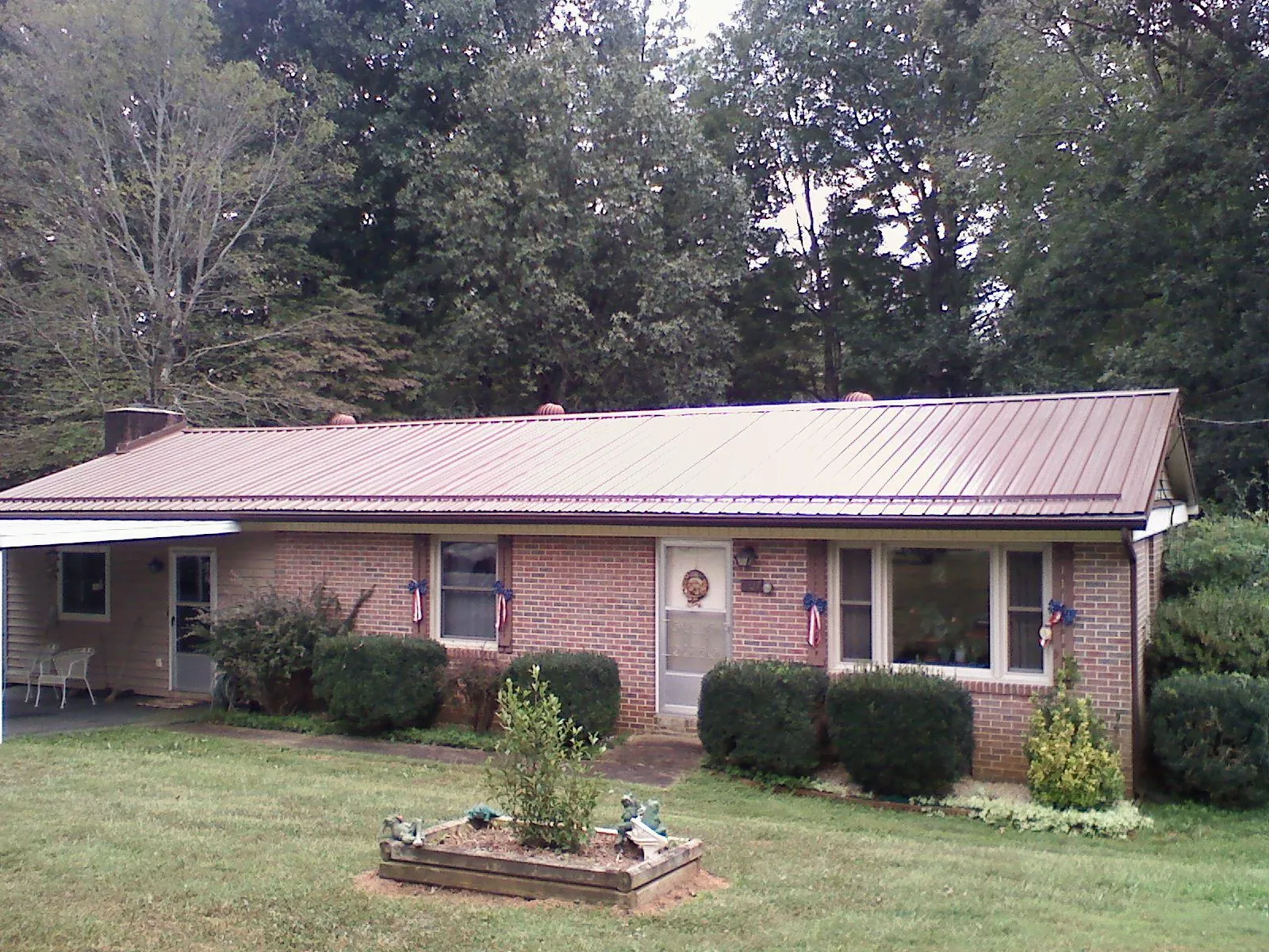 Bronze metal roof on a brick ranch home with a carport in Preston