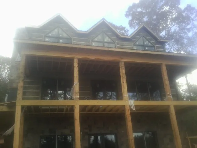 Dormers and porch framing on a large log home under construction — Roof Coating work by our crew in Preston